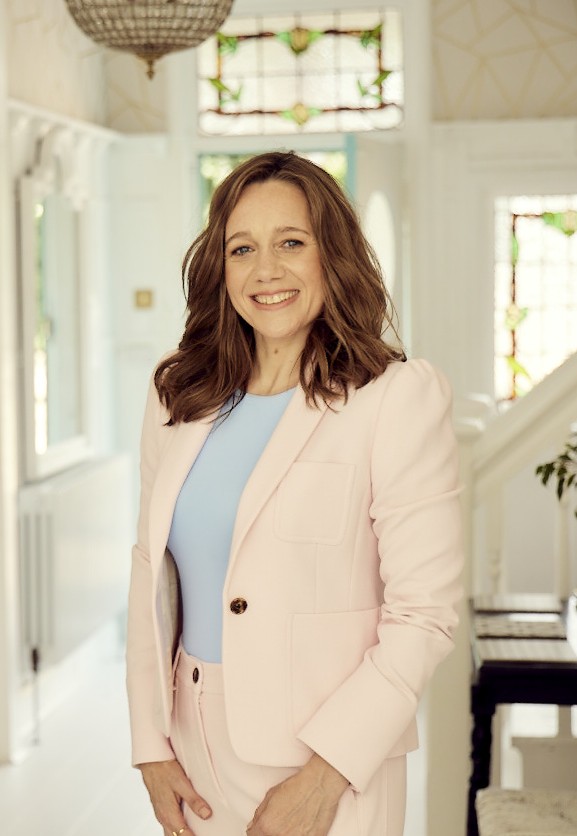 Karen Knowler smiling, standing in a bright hallway